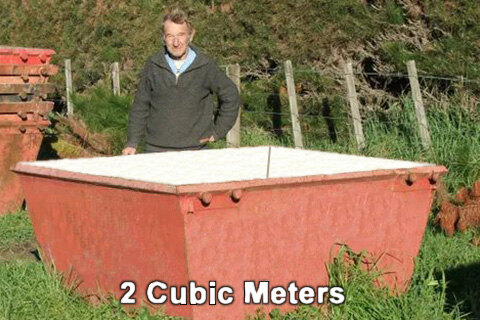 The red 2 cubic metre Canterbury Mini Skips bin standing in a paddock with an owner-operator beside it