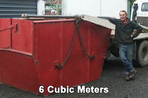 The red 6 cubic metre Canterbury Mini Skips bin with lifting hooks and chain laid across its side
