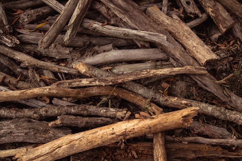A close-up of rough split timber and logs stacked in a heap, ready to be loaded